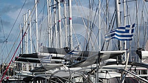 Three Greek flags, and one French, blowing in the wind at a yacht harbor