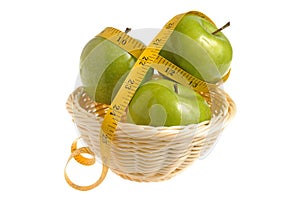 Three green apples wrapped with measuring tape in the wicker basket isolated