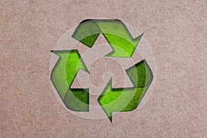 The three green arrows going in a triangle, international recycle symbol on Brown Cardboard. Paper or cardboard eco friendly