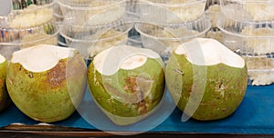 Three green coconuts on a blue table