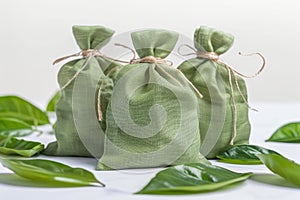 Three green fabric pouches on light background with leaves photo