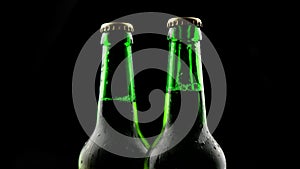 Three green glass beer bottles spinning on a black background in the dark