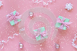 Three green present boxes with bow on pink background with boubles and confetti. Christmas concept. Top view, flat lay