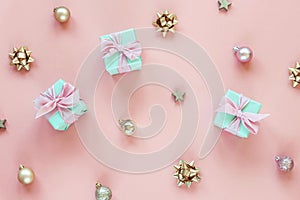 Three green present boxes with bow on pink background with Christmas balls and boubles. Holidays concept. Top view, flat lay