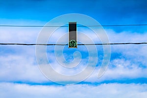 Three green traffic lights hang over the road against the blue sky. Allow signal.