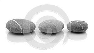 Three grey stones mirrored on white surface