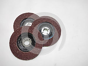Three (grinding wheels) abrasive flap discs arranged on a white surface