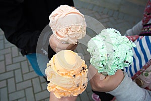 Three guys holding ice creems on their hands