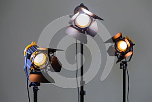 Three halogen spotlights with Fresnel lenses on a grey background. Photographing and filming in the interior