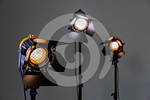 Three halogen spotlights with Fresnel lenses on a grey background. Photographing and filming in the interior