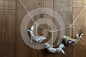 Three handmade fabric bird decorations on a wood background.