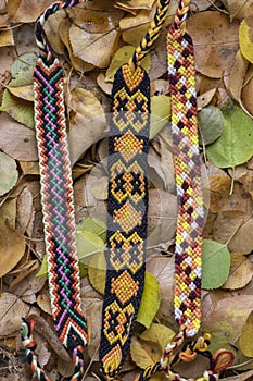 Three handmade homemade colorful natural woven bracelets of friendship in autumn dry leaves