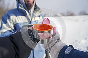 Three hands hold thermo mugs with coffee