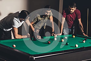 three handsome caucasian men playing in billiard