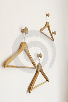 Three hangers hanging on hooks on a white wall