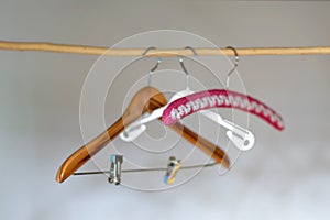 Three hangers, made of wood, plastic and crochet  hanging on a wooden bar