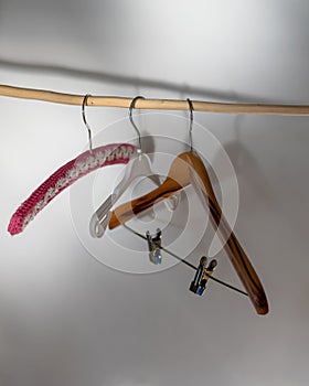 Three hangers, made of wood, plastic and crochet  hanging on a wooden bar