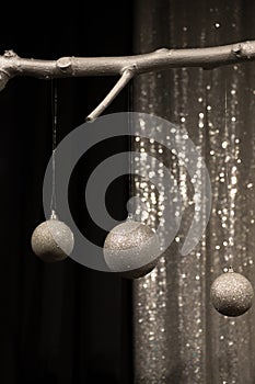 Three hanging silver Christmas balls on dark and silver background