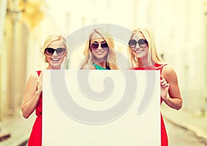 Three happy blonde women with blank white board