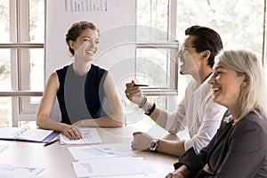 Three happy businesspeople talking gathered in conference room