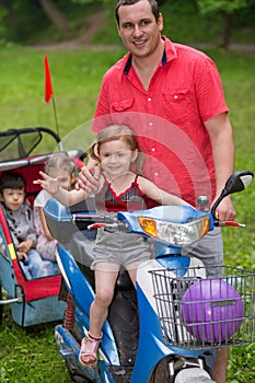 Three happy children with father on a scooter with