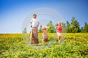 Three happy children jumping in sacks during play