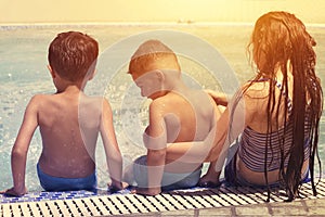 Three happy children playing on the swimming pool at the day time. Summer vacation concept.
