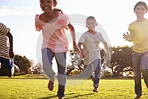 Three happy children running barefoot in a field in Summer