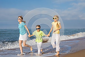 Three happy children running on the beach at the day time.