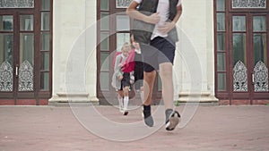 Three happy children running from school after studying. Wide shot portrait of cheerful Caucasian boy and girls