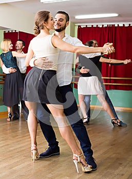 Three happy couples dancing tango