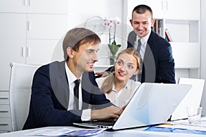 Three happy coworkers working in company office