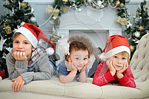 Three happy cute children in santa caps lie on