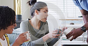 Three happy, diverse female and male friends having coffee at home, in slow motion