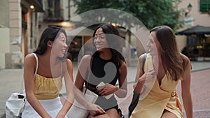 Three happy diverse women female friends chatting and laughing while spending time together outdoor