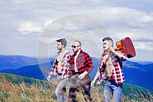 Three happy friends are looking on mountains and having fun together. Group of friends on country walk on a summer day