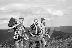 Three happy friends are looking on mountains and having fun together. Group of friends on country walk on a summer day