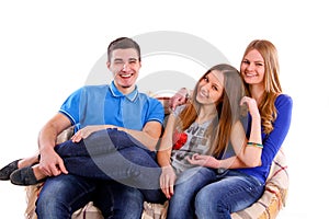 Three happy friends sitting on a couch isolated