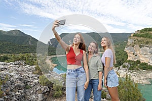 Three happy friends taking selfie in the mountain