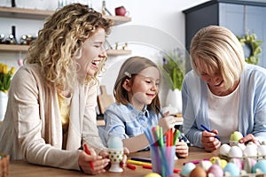 Three happy generations of women decorate easter eggs