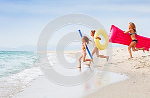 Three happy girls running together in tropical sea