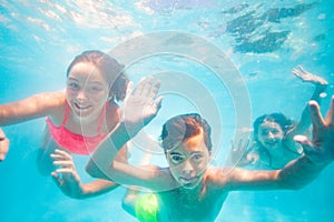 Three happy kids friends swim have fun underwater