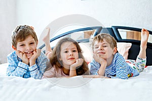 Three happy kids in pajamas celebrating pajama party. Preschool and school boys and girl having fun together