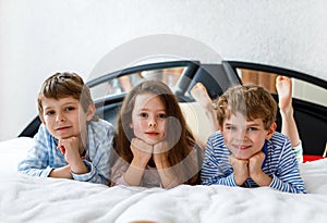 Three happy kids in pajamas celebrating pajama party. Preschool and school boys and girl having fun together