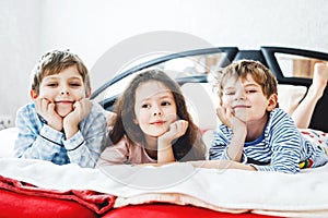 Three happy kids in pajamas celebrating pajama party. Preschool and school boys and girl in nightwear having fun
