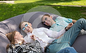 Three happy laughing friends chilling outdoors in the park on a