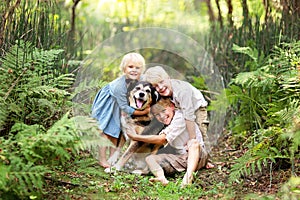 Three Happy Children Lovinglt Hugging the Pet Dog in the Forest photo