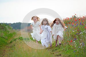 Three happy little girls running on the field