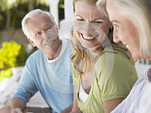 Three Happy Mature People Sitting On Verandah photo