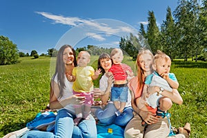 Three happy mothers holding cute babies in park